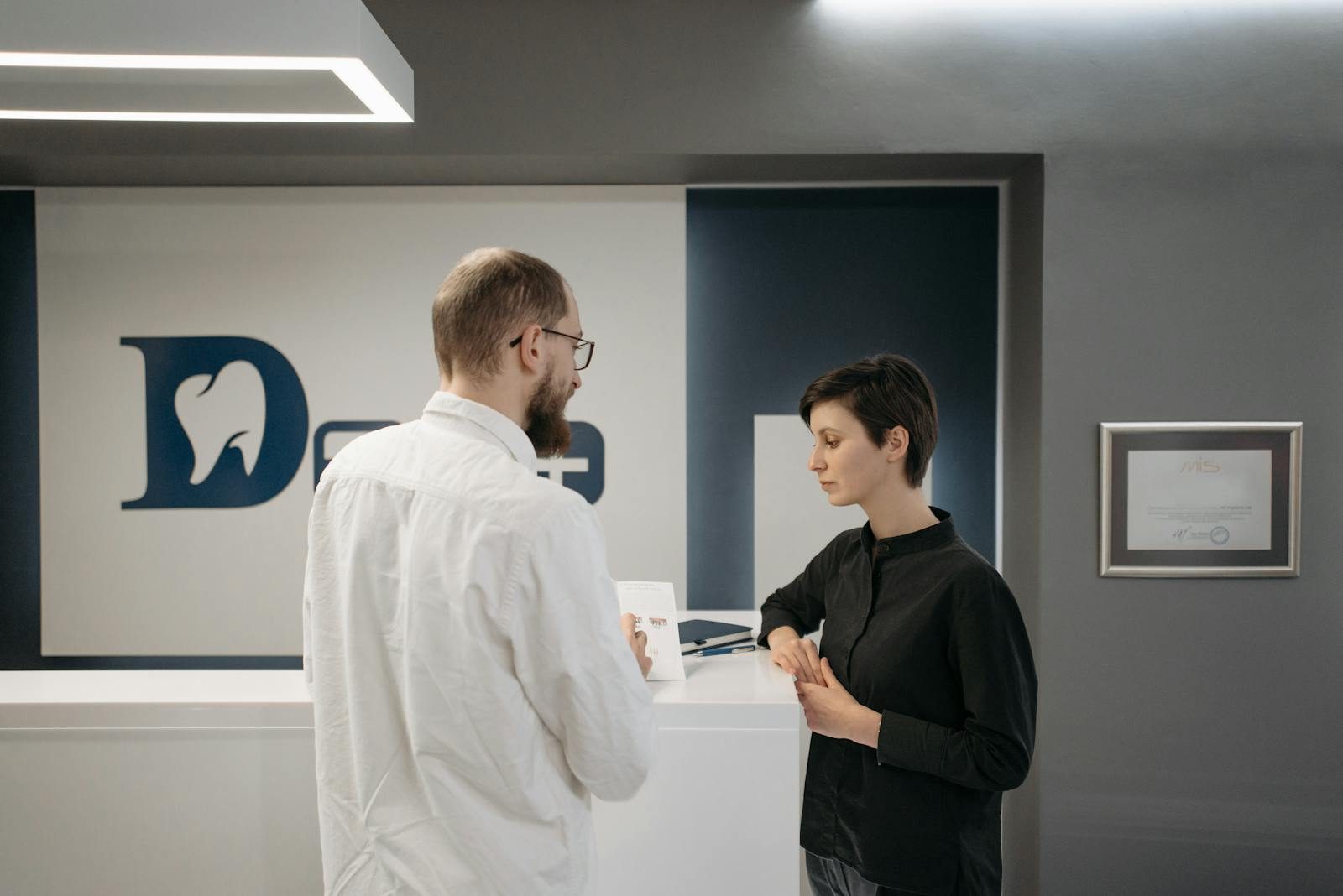 A patient and staff member at a modern dental clinic reception desk